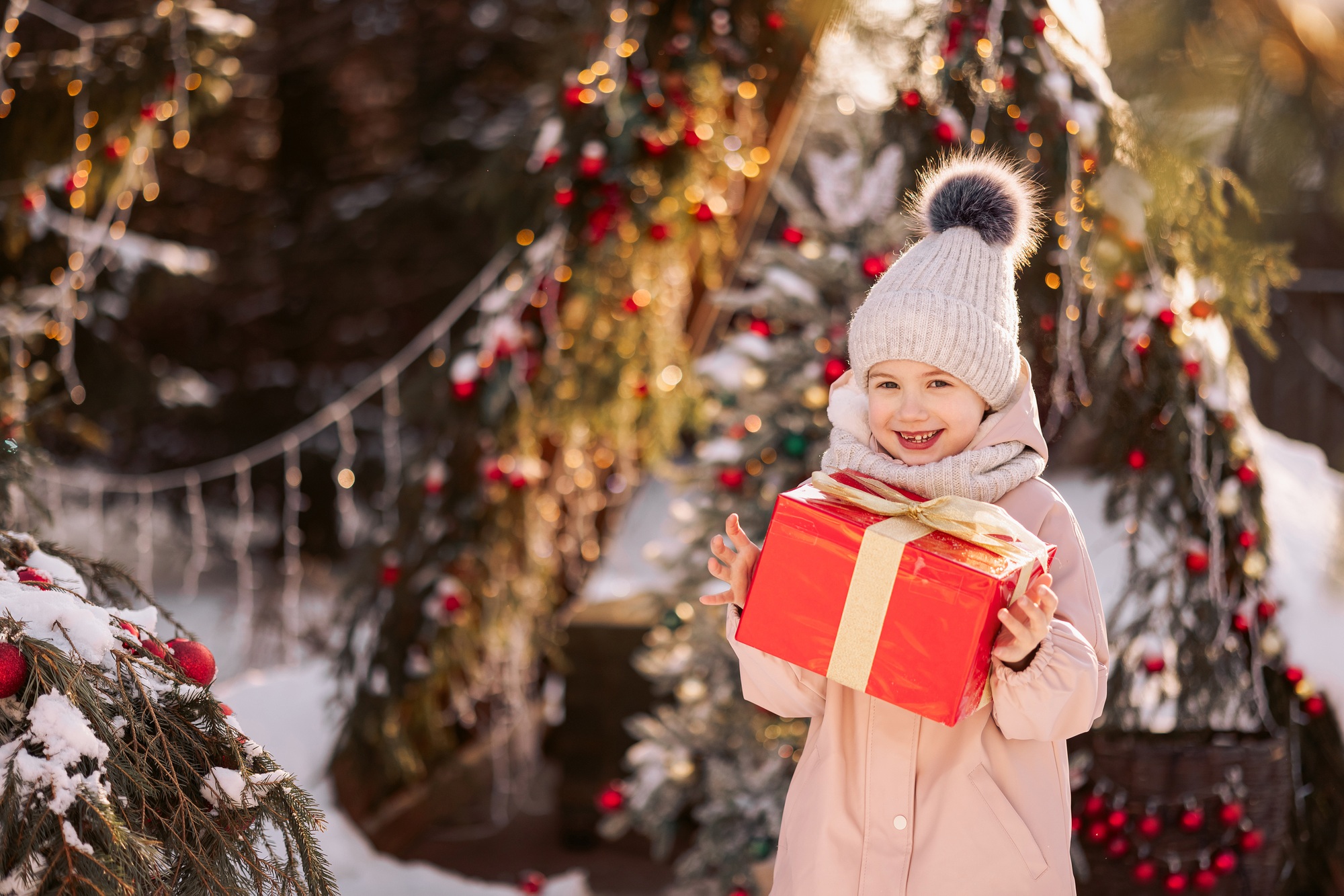 Little girl with a Christmas gift outdoors in winter on Christmas Eve.